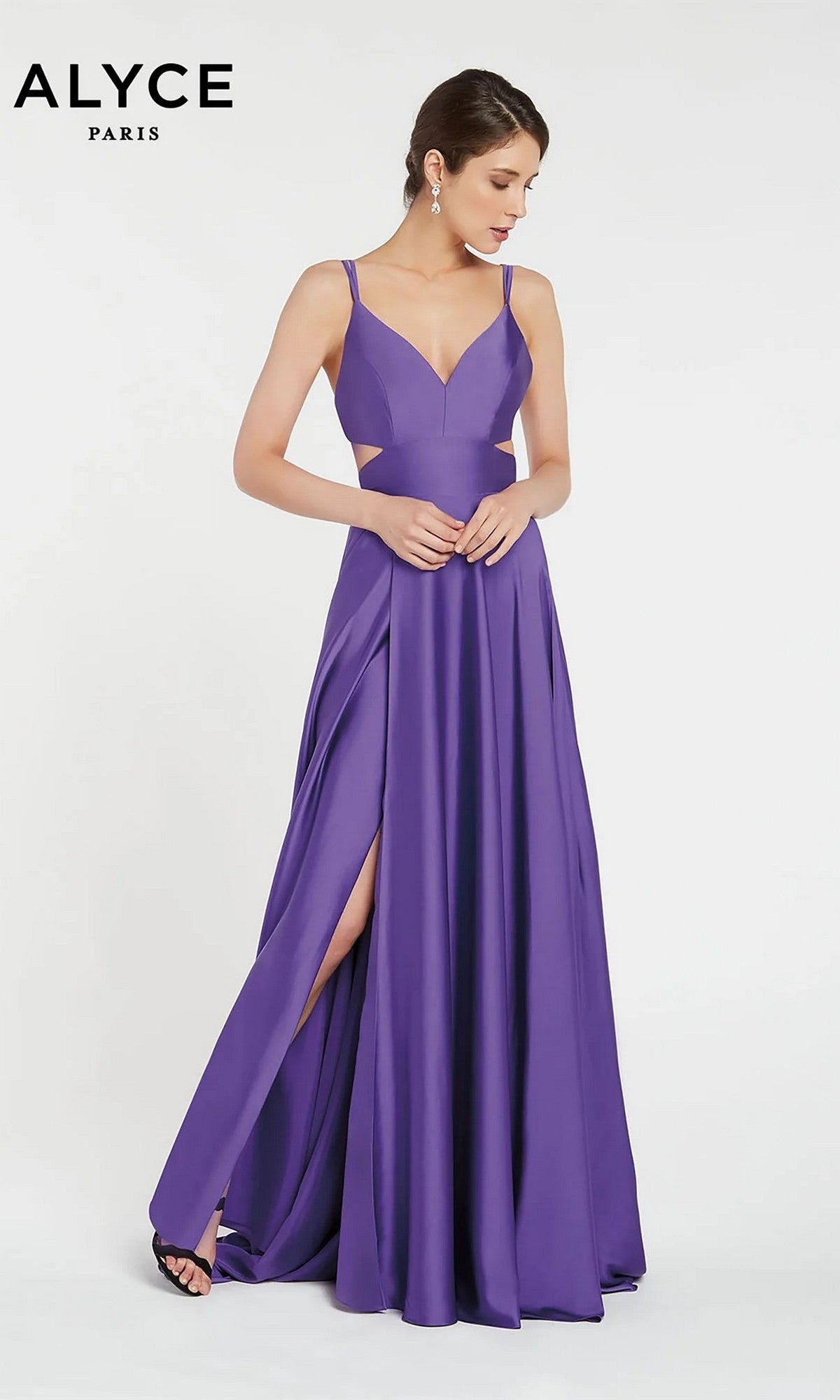 A woman stands against a white background wearing the Alyce 60453 Long Formal Dress in purple, a floor-length satin gown with thin straps, side cutouts, a high slit, and sleeveless design.